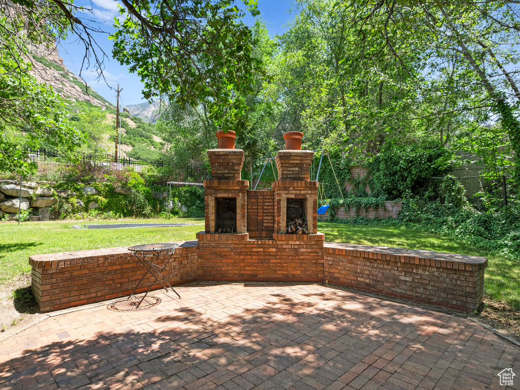 View of patio with an outdoor brick fireplace and a mountain view