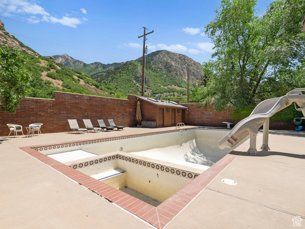 View of pool featuring a water slide, a mountain view, a patio area, and a fenced backyard