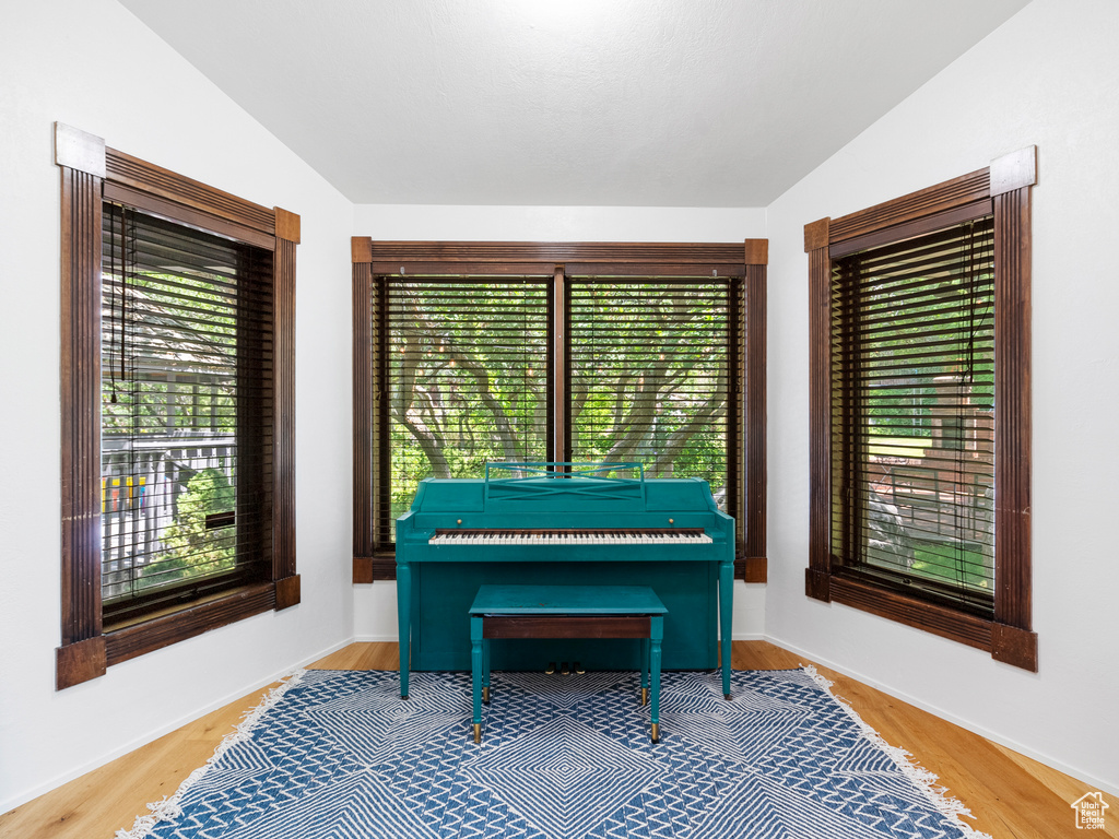 Sitting room with lofted ceiling, healthy amount of natural light, and wood finished floors