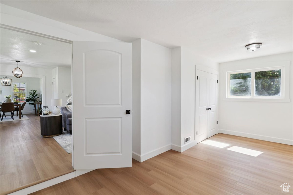 Hall with light wood-type flooring and a chandelier