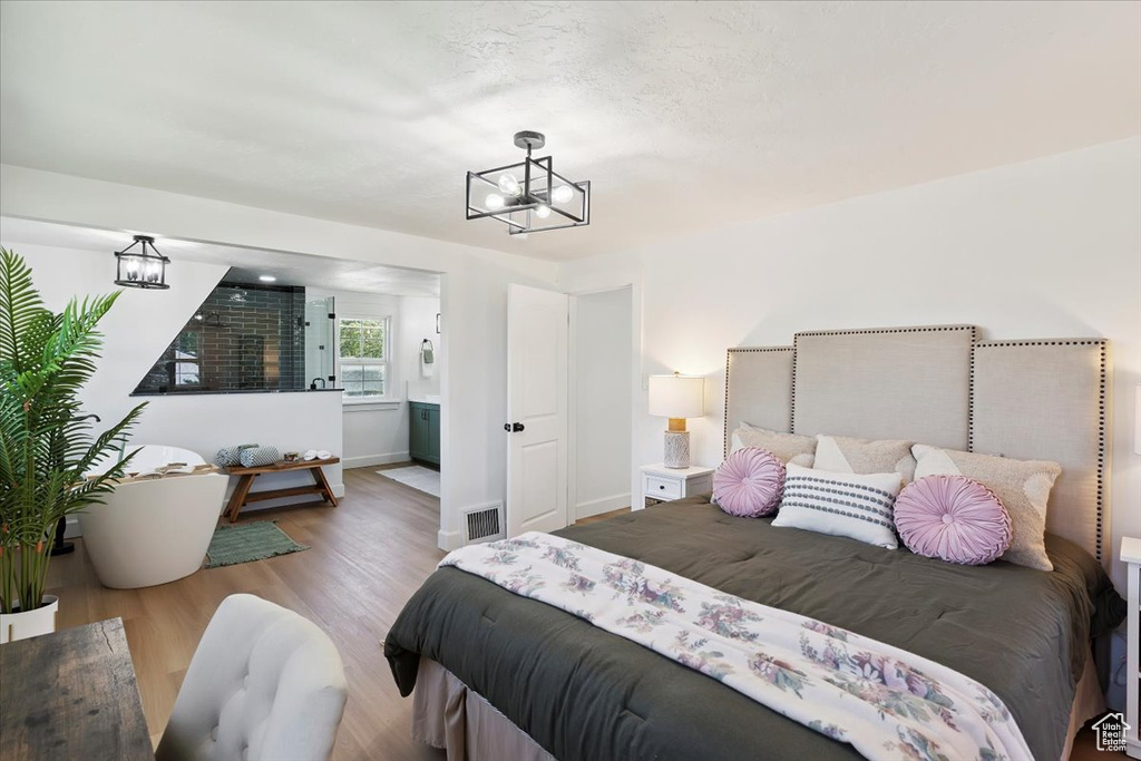 Bedroom featuring a chandelier, wood finished floors, and ensuite bathroom