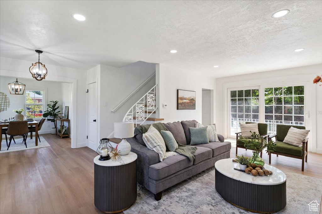 Living area featuring stairway, wood finished floors, a chandelier, healthy amount of natural light, and recessed lighting