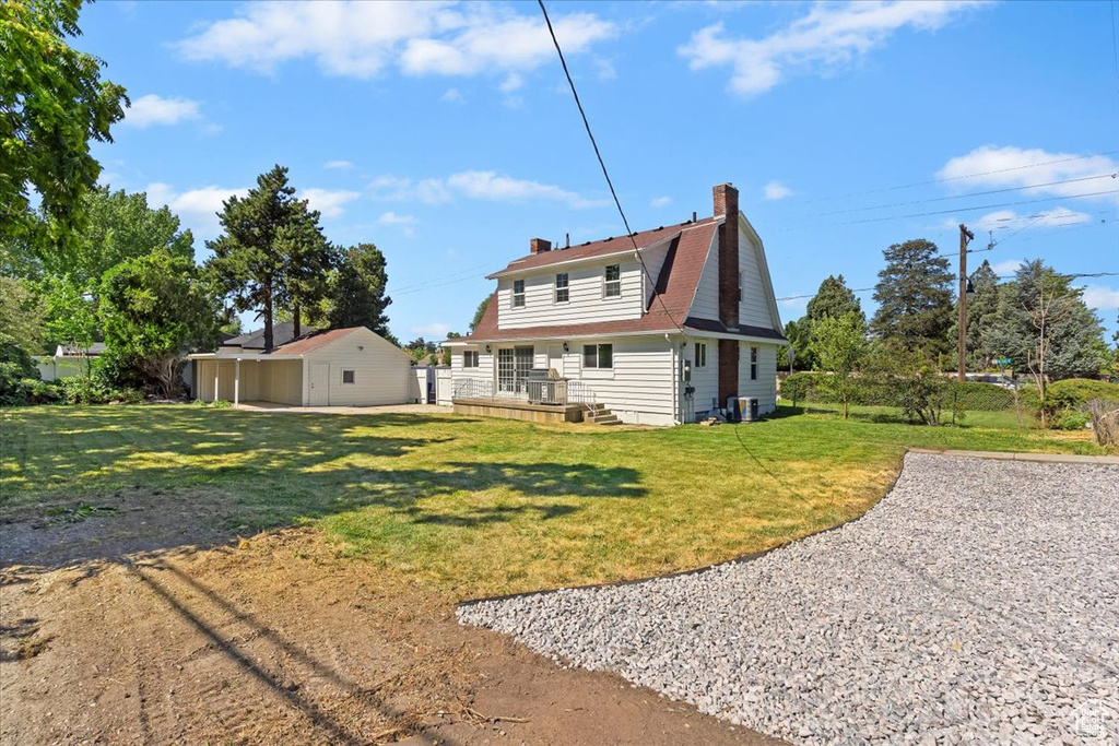 Back of property featuring a chimney, a yard, and a gambrel roof