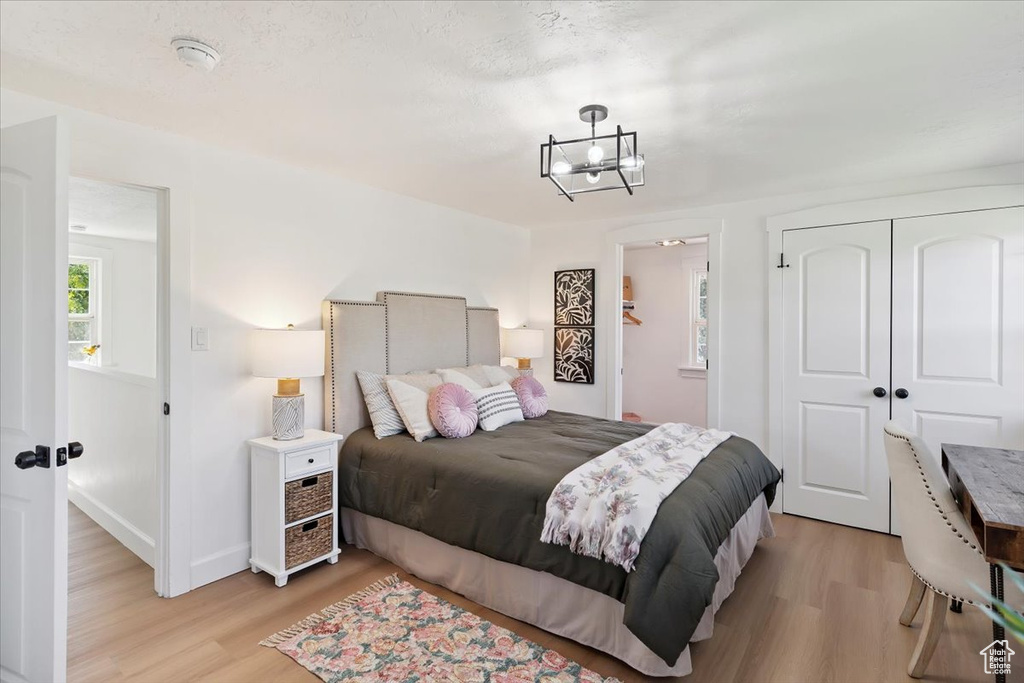 Bedroom with light wood-style floors, a chandelier, and a closet