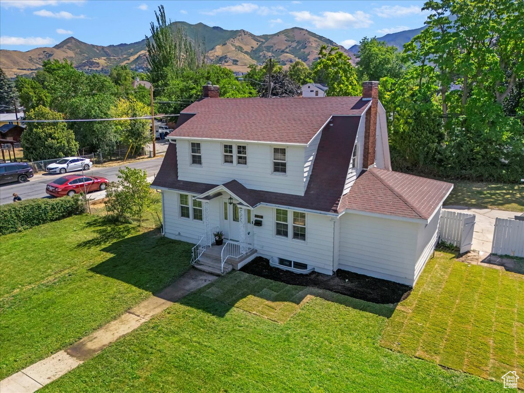 View of front of house with a chimney, a mountain view, and roof with shingles