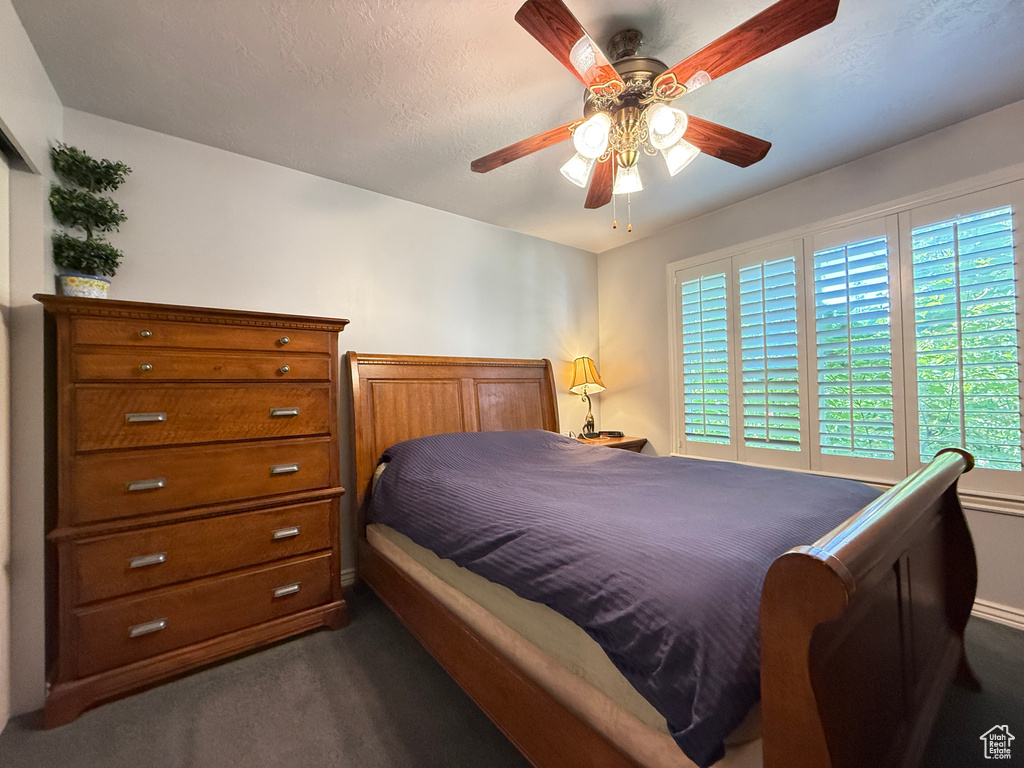 Bedroom with dark carpet and a ceiling fan