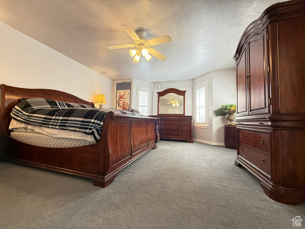 Bedroom featuring light colored carpet, a ceiling fan, and a textured ceiling