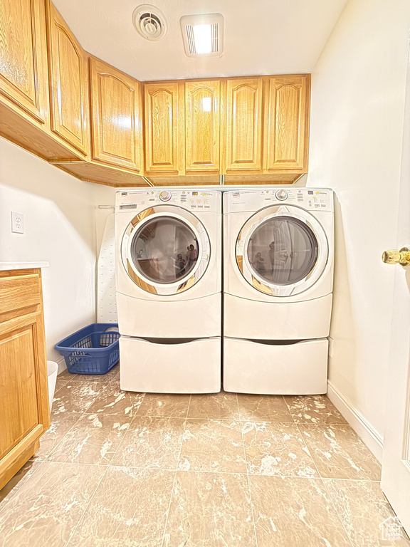 Laundry room with cabinet space, independent washer and dryer, and light tile patterned flooring