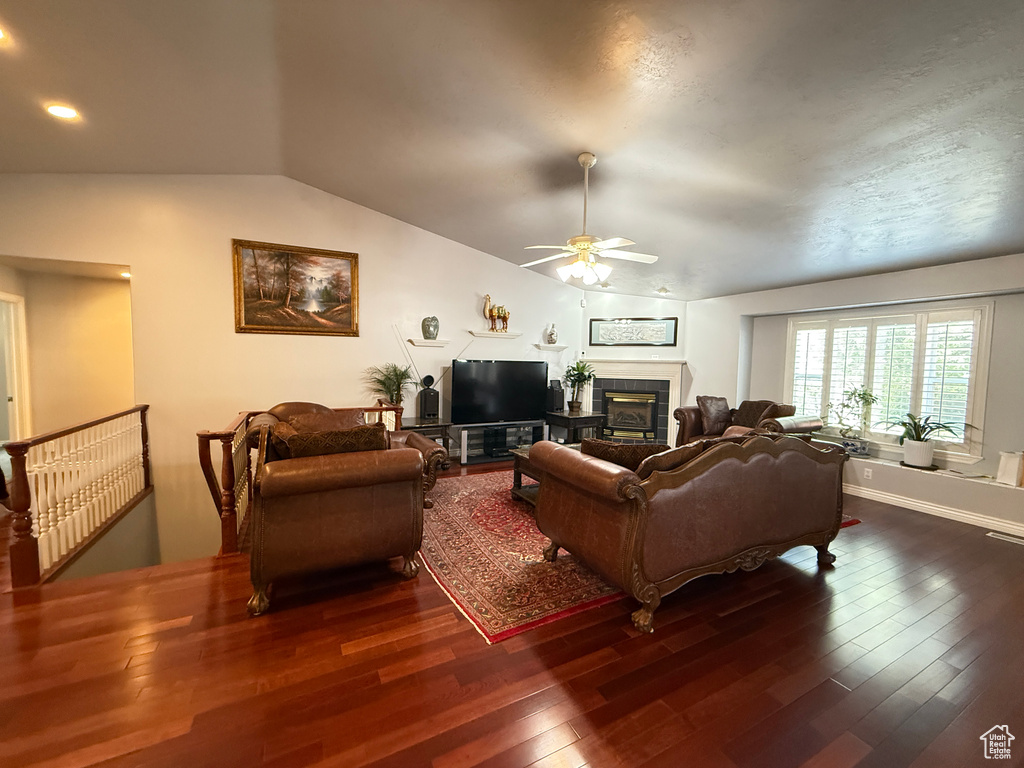 Living area featuring ceiling fan, vaulted ceiling, hardwood / wood-style flooring, and a tile fireplace