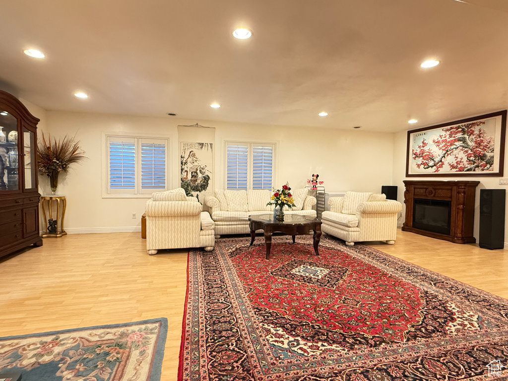 Living area with light wood-style floors, recessed lighting, and a glass covered fireplace