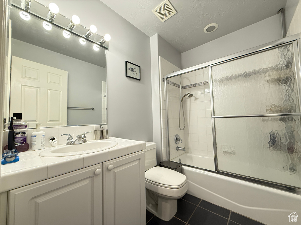 Bathroom featuring vanity, tile patterned flooring, and enclosed tub / shower combo