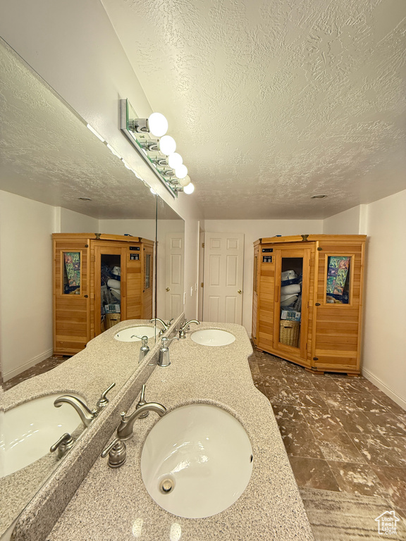 Bathroom with a textured ceiling and double vanity