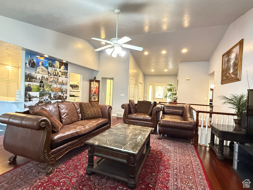 Living area featuring dark wood-style floors, ceiling fan, and vaulted ceiling
