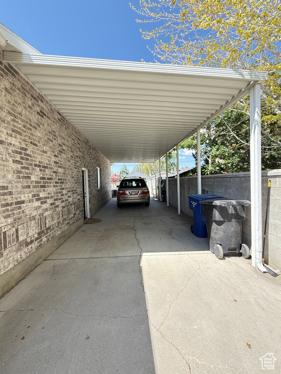 View of parking / parking lot with concrete driveway and a carport