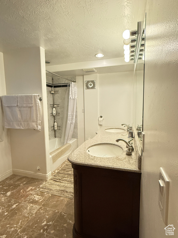 Bathroom with double vanity, a textured ceiling, and shower / bath combo