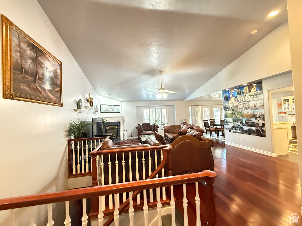 Living area with a glass covered fireplace, lofted ceiling, dark wood-style flooring, ceiling fan, and recessed lighting