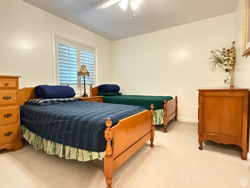 Bedroom with light colored carpet and a ceiling fan