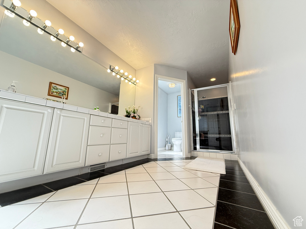 Bathroom featuring a stall shower, double vanity, tile patterned floors, a bidet, and a textured ceiling