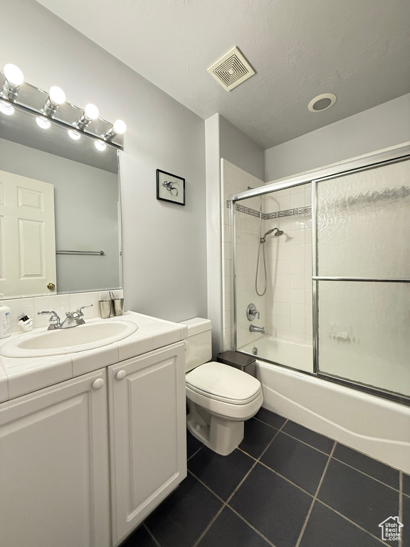 Full bathroom featuring vanity, tile patterned flooring, and combined bath / shower with glass door