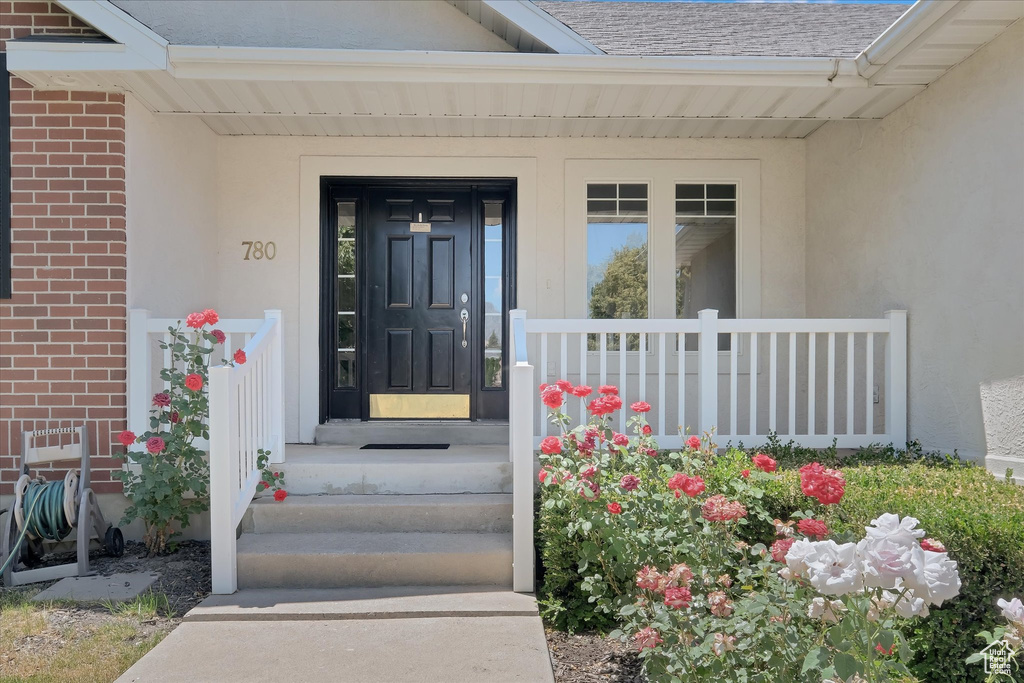 Doorway to property with brick siding, roof with shingles, and stucco siding