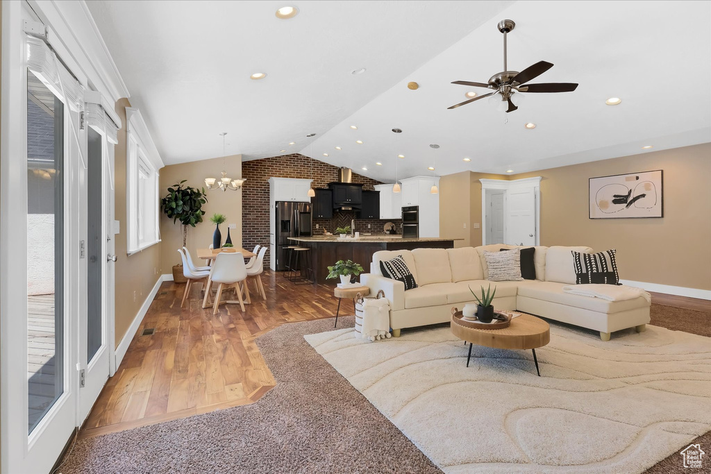 Living area with vaulted ceiling, ceiling fan, wood finished floors, recessed lighting, and a chandelier