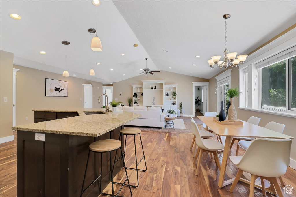 Dining room featuring vaulted ceiling, light wood finished floors, recessed lighting, a chandelier, and a ceiling fan