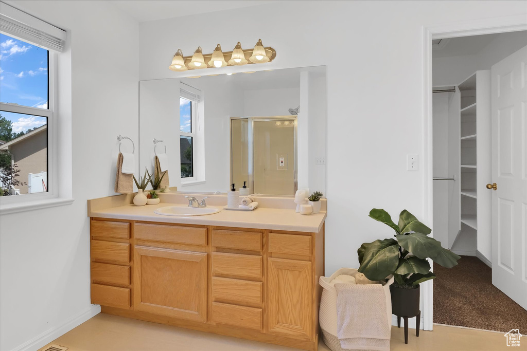 Full bath featuring vanity, a stall shower, and a spacious closet