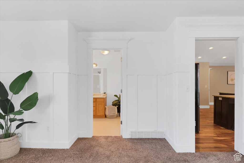Hall with carpet floors, wainscoting, a decorative wall, and recessed lighting