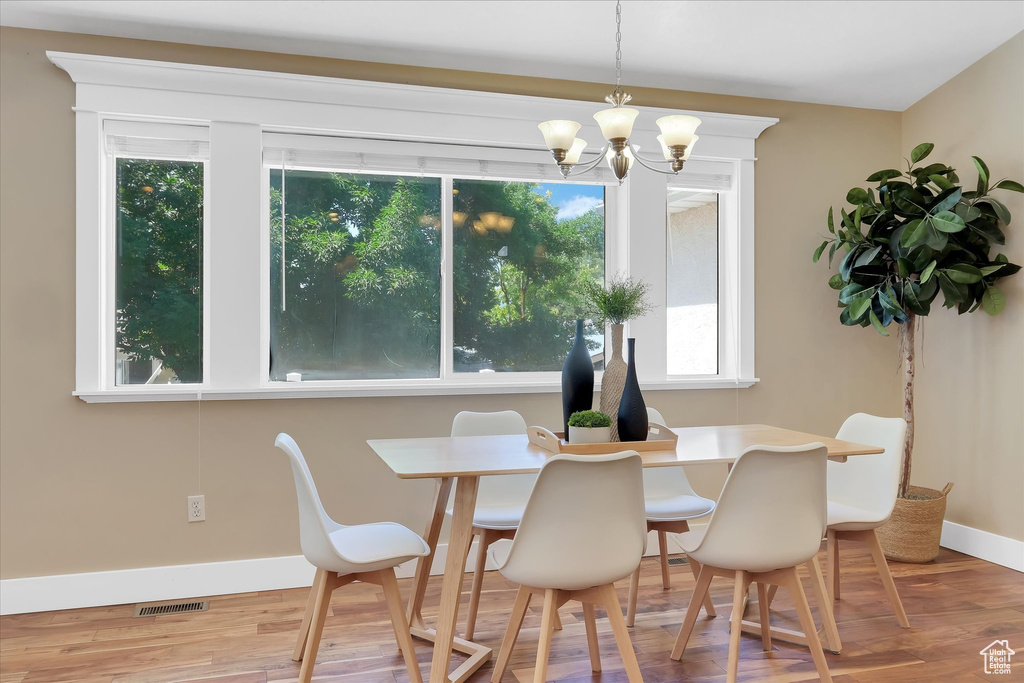 Dining room featuring healthy amount of natural light, a chandelier, and wood finished floors