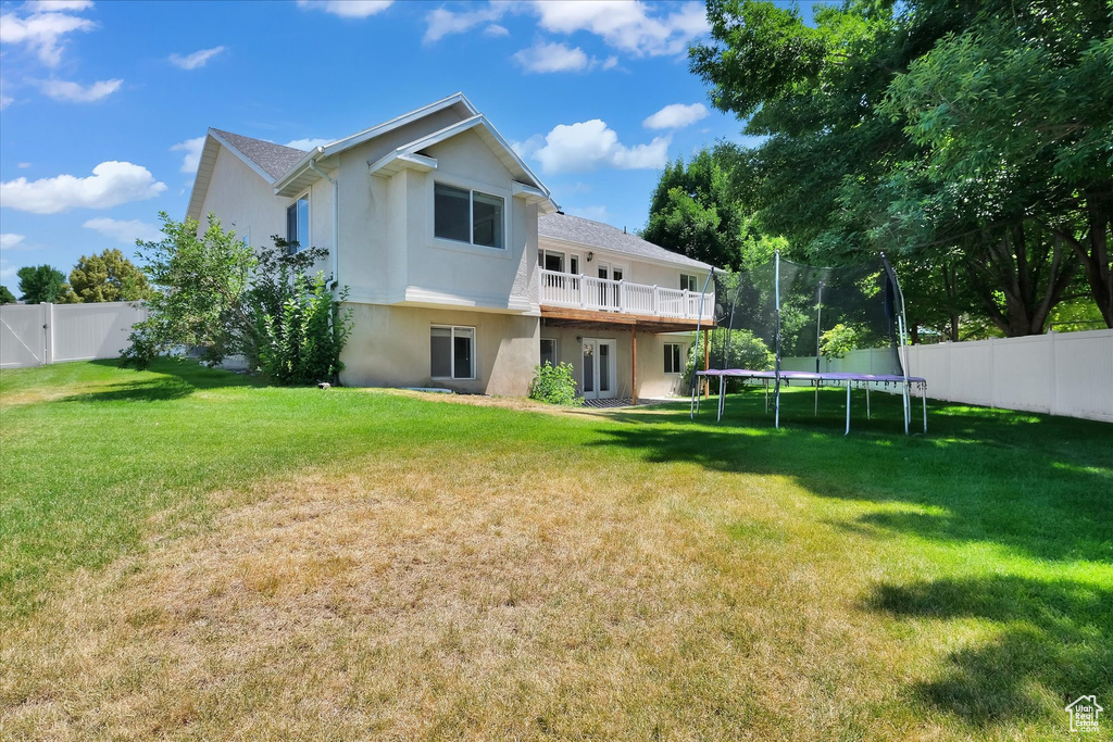 Rear view of property featuring stucco siding, a fenced backyard, and a trampoline