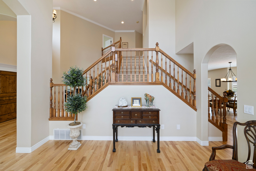 Stairway featuring wood finished floors, arched walkways, a towering ceiling, a chandelier, and recessed lighting
