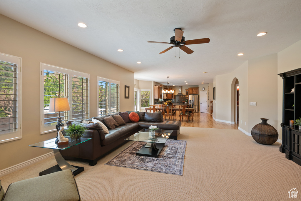 Living area with recessed lighting, light colored carpet, ceiling fan, plenty of natural light, and arched walkways