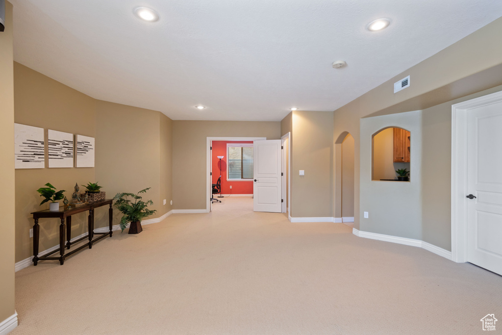 Spare room featuring light carpet, recessed lighting, a smoke detector, and arched walkways