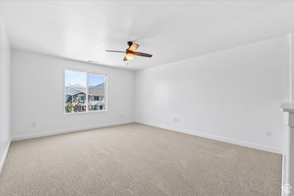 Spare room featuring a ceiling fan and light colored carpet