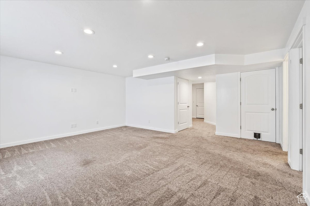 Finished basement with light colored carpet and recessed lighting