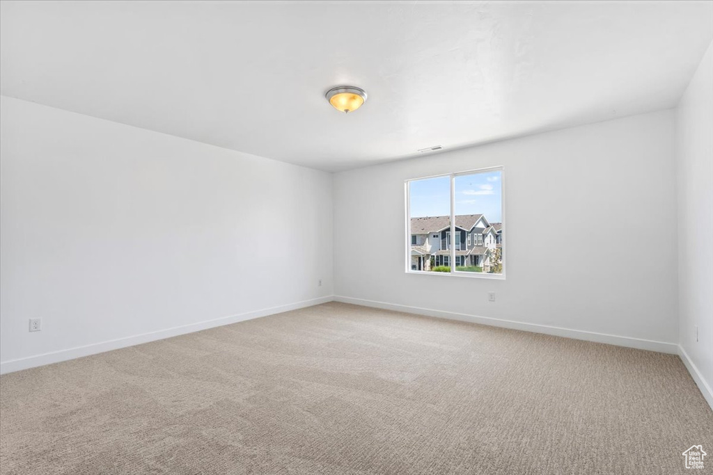 Unfurnished room featuring baseboards and light carpet