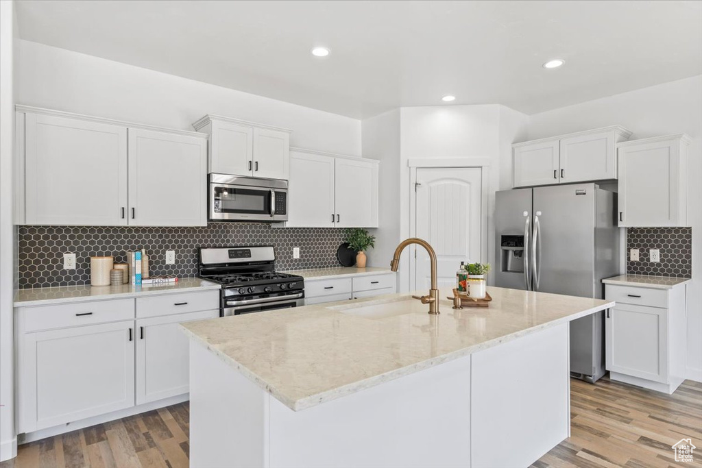Kitchen with appliances with stainless steel finishes, decorative backsplash, white cabinetry, a center island with sink, and recessed lighting