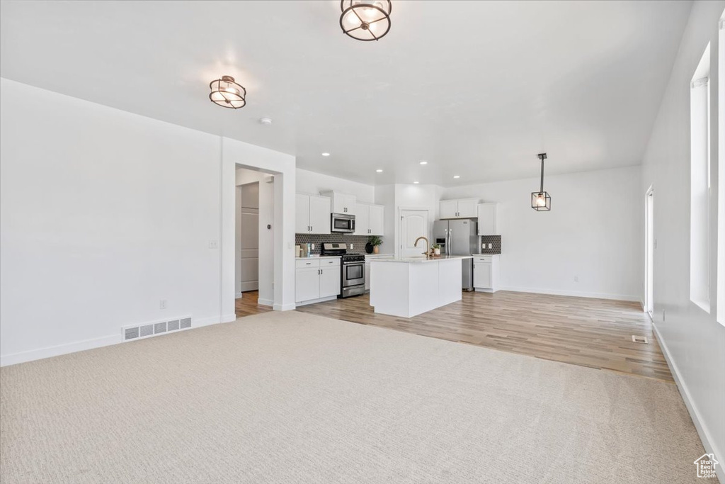 Unfurnished living room featuring light carpet, recessed lighting, and light wood-style flooring