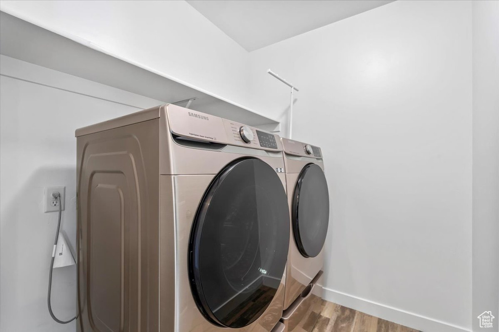 Laundry area featuring independent washer and dryer and wood finished floors