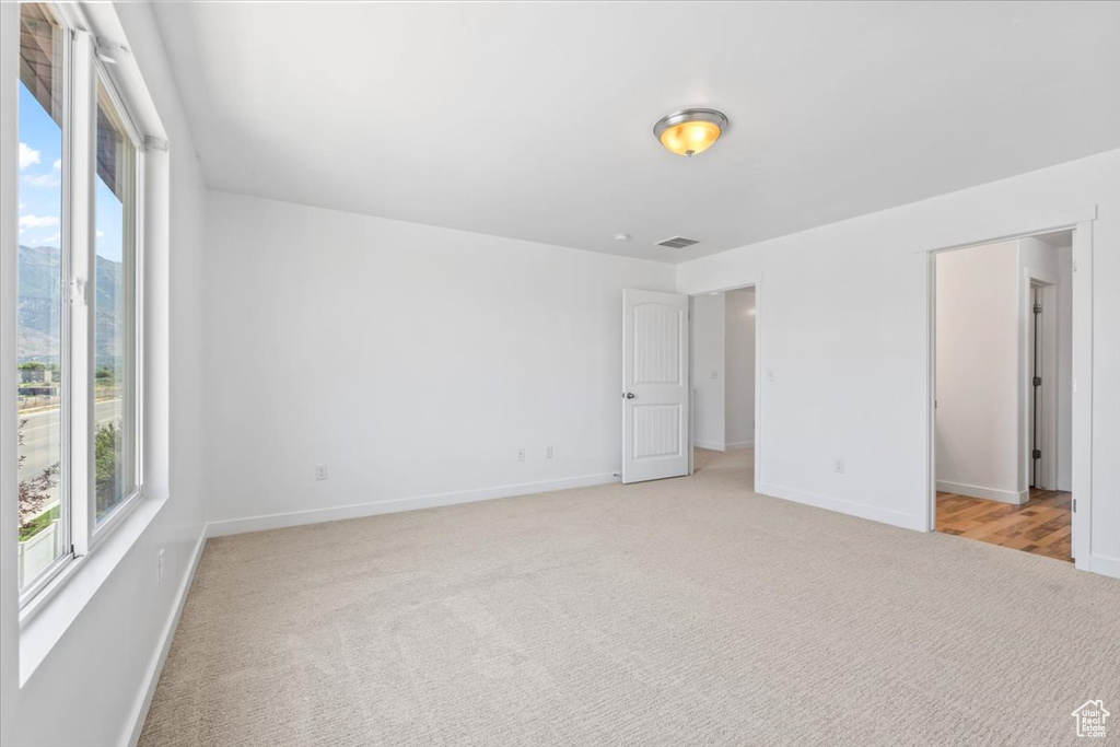 Unfurnished bedroom featuring light carpet and baseboards