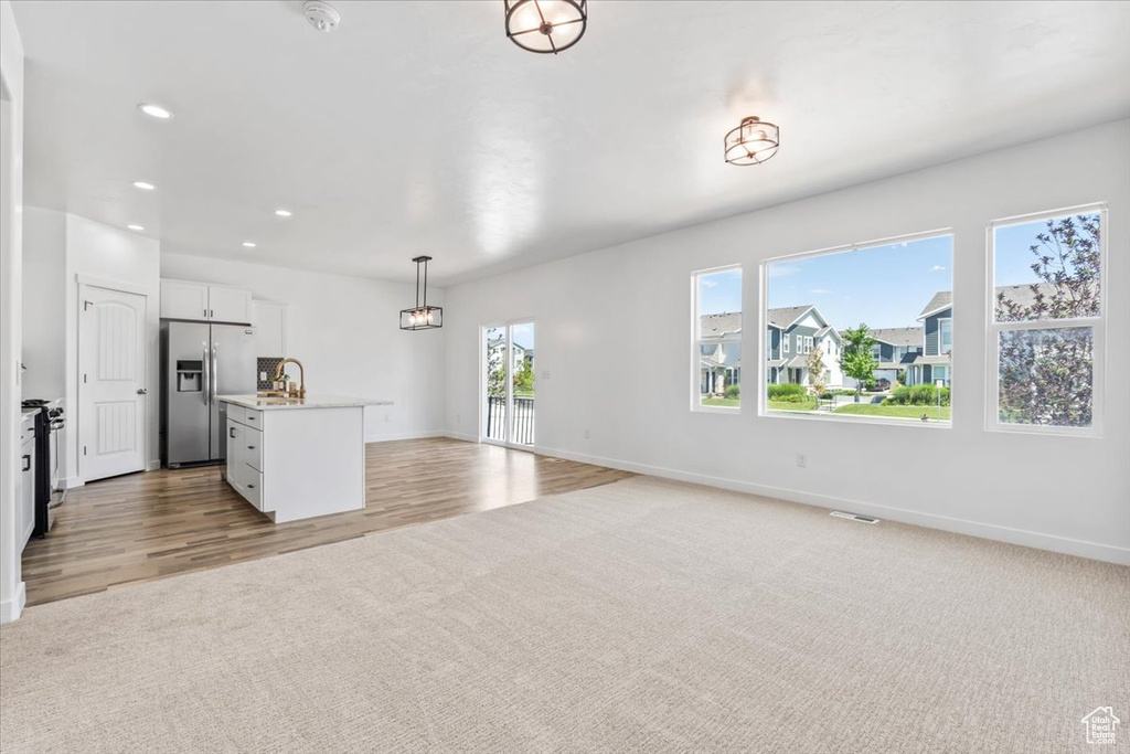 Unfurnished living room featuring recessed lighting, light wood finished floors, and light colored carpet