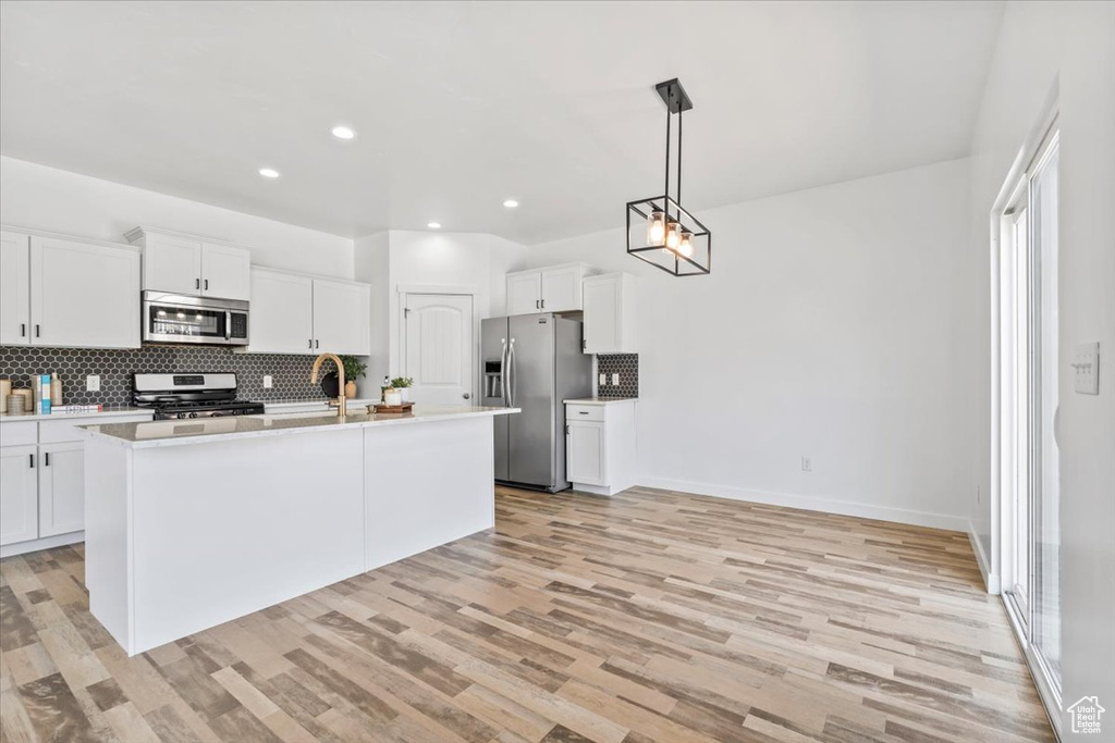Kitchen with appliances with stainless steel finishes, decorative backsplash, light countertops, light wood-style floors, and recessed lighting