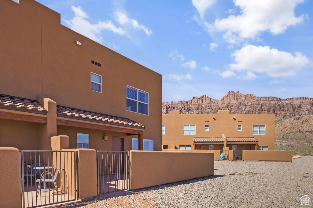 Back of property featuring a tiled roof, stucco siding, a gate, and a mountain view