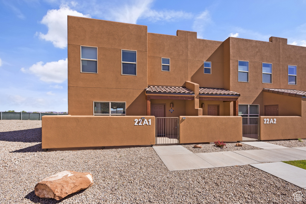 View of front of house with a fenced front yard, a gate, stucco siding, and a tile roof
