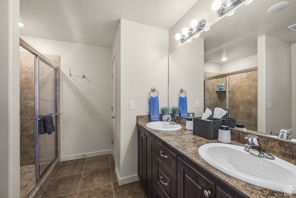 Full bathroom with double vanity, a stall shower, and tile patterned flooring