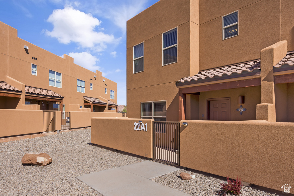 View of front of property with a fenced front yard, a gate, stucco siding, a tiled roof, and a residential view
