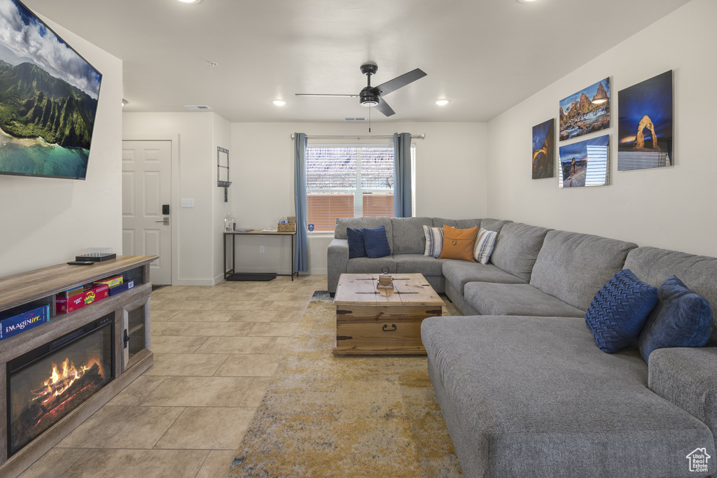 Living room with ceiling fan, recessed lighting, a glass covered fireplace, and light tile patterned floors