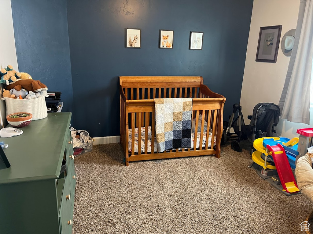 Bedroom featuring a crib and carpet floors