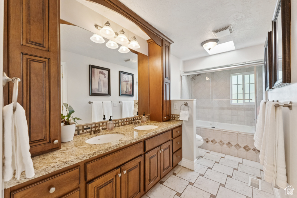 Bathroom with double vanity, tiled shower / bath, and tile patterned flooring