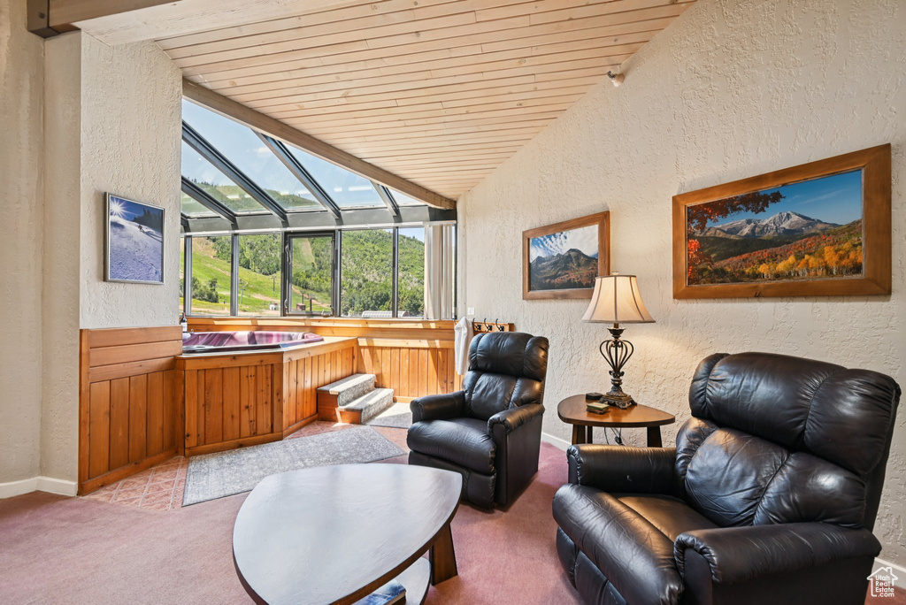 Living area with a textured wall, lofted ceiling, wooden ceiling, light carpet, and a sunroom